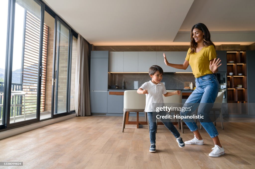 Happy mother having fun dancing with her son at home