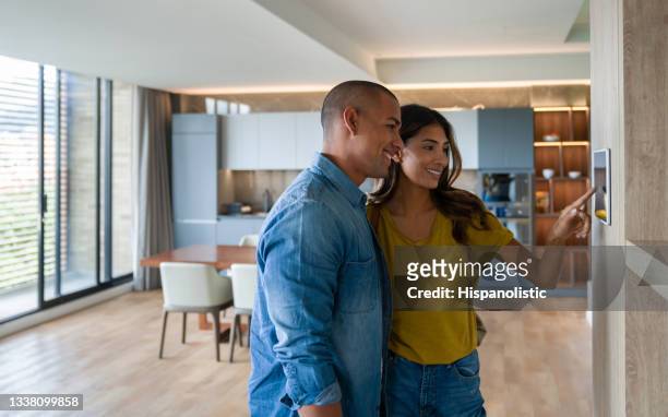 pareja que controla las características de su casa utilizando un sistema automatizado desde una tableta - thermostat fotografías e imágenes de stock