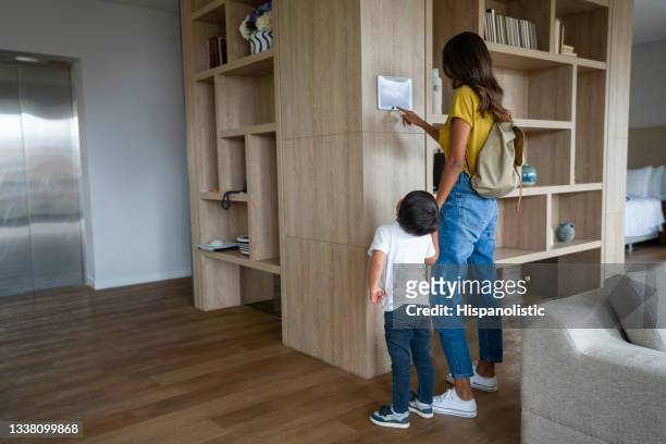 woman leaving the house with her son and locking the door using a home automation system - alarm system stock pictures, royalty-free photos & images