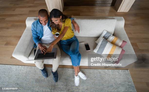 happy couple relaxing at home and looking at social media on their laptop - young couple watching tv stock pictures, royalty-free photos & images