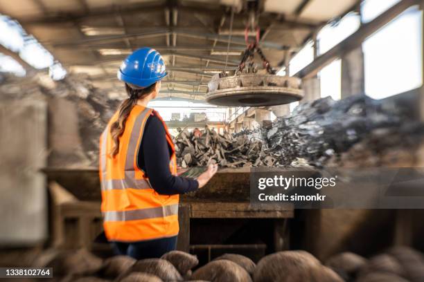 rear view of female engineer inspecting scrap in scrap yard - spare parts stock pictures, royalty-free photos & images