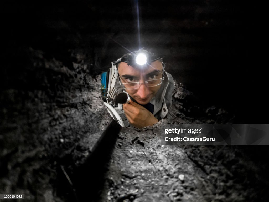 Man with a head torch Looking Inside a Hole