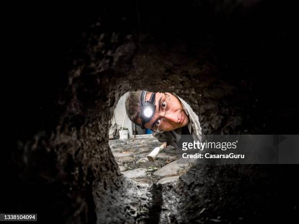 portrait of a young man looking inside a rodent hideout - spy hunter stock pictures, royalty-free photos & images
