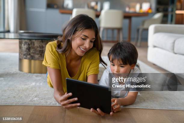happy mother and son at home watching a movie together on a tablet - family ipad stockfoto's en -beelden