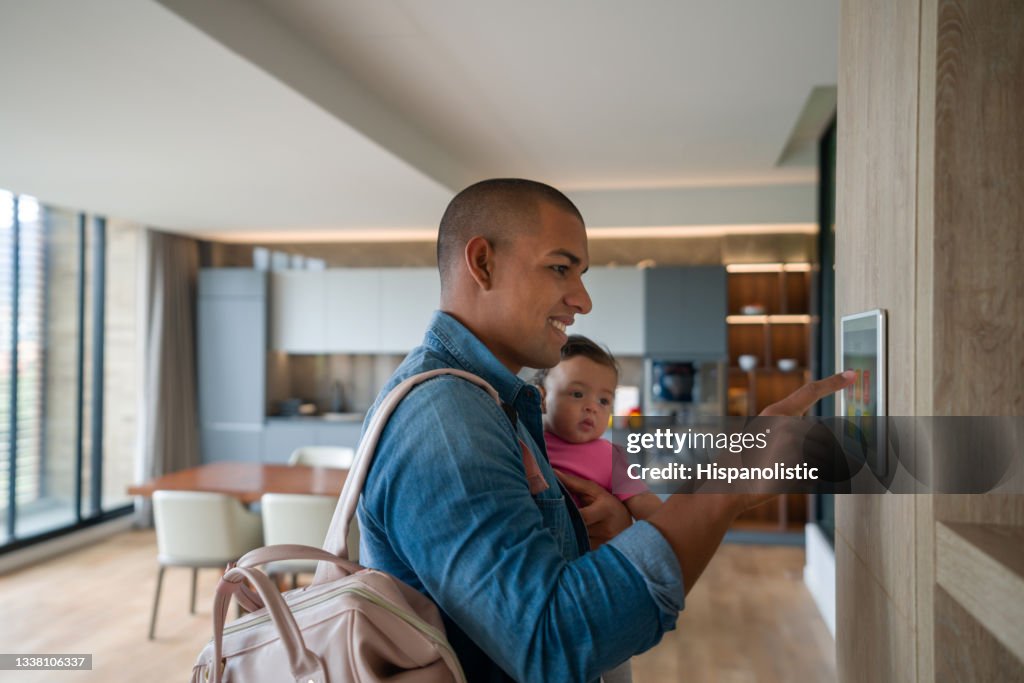Hombre saliendo de casa con su bebé y cerrando la puerta con un sistema domótico