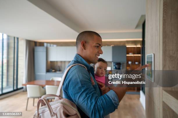 man leaving the house with his baby and locking the door using a home automation system - burglar alarm stock pictures, royalty-free photos & images