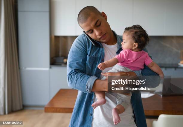 padre ocupado haciendo múltiples tareas en casa cargando al bebé mientras habla por teléfono - man looking upset fotografías e imágenes de stock