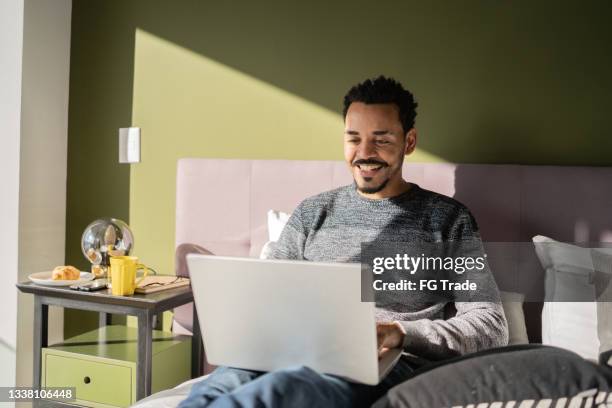 man typing or watching something on the laptop at home - goatee stockfoto's en -beelden