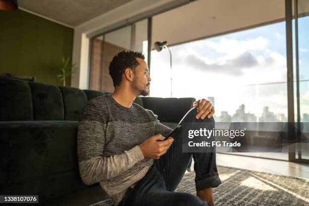 contemplative man looking away using smartphone at home - fast forward bildbanksfoton och bilder