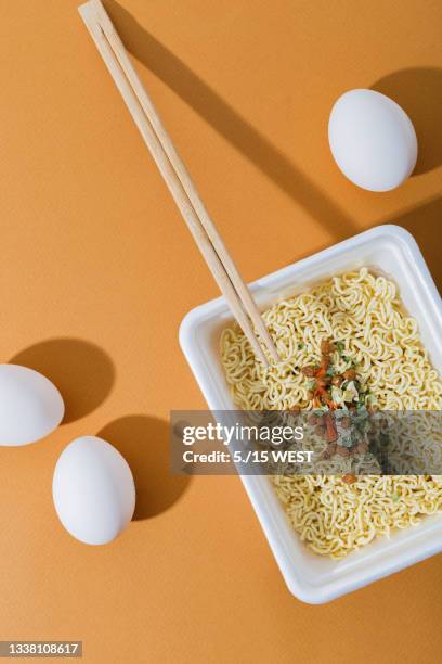 instant noodles with egg and meat, in a plastic plate. fast, nourishing lunch and dinner every day. orange background, top view - instant noodles stock pictures, royalty-free photos & images