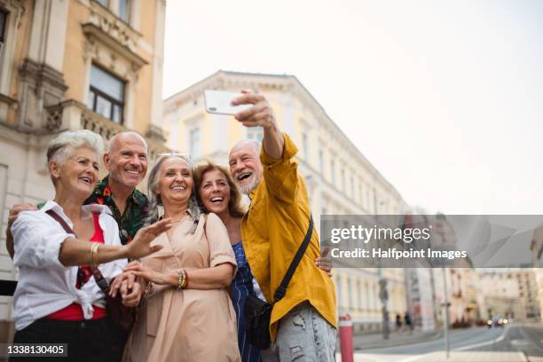 group of happy senior friends tourists on a walk in city, taking selfie. - selfie group stockfoto's en -beelden