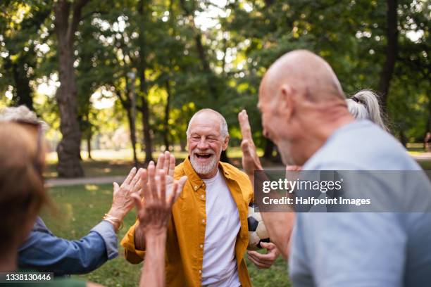 group of happy senior friends tourists having fun in city park, playing football. - city 70's fotografías e imágenes de stock