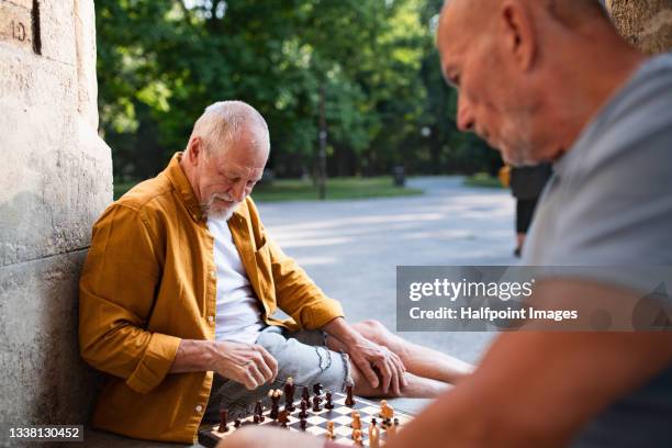 happy senior men friends tourists sitting outdoors in city, playing board games. - chess photos et images de collection