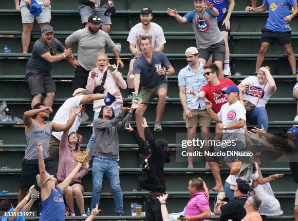 Fans in the left field bleachers try to catch the home run ball hit by Frank Schwindel of the Chicago Cubs during the sixth inning of a game against...