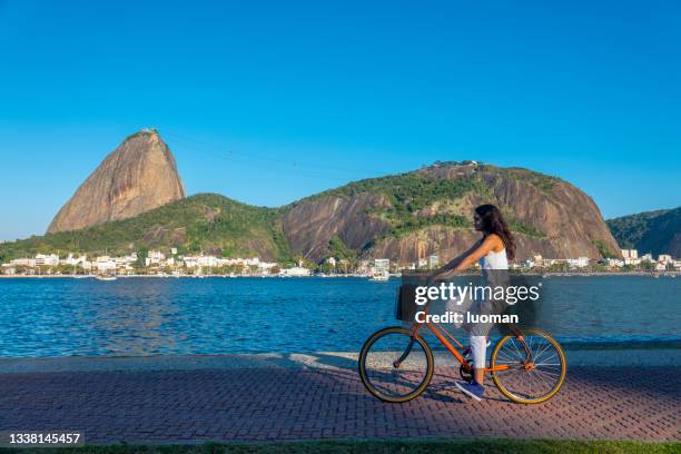 young woman rides a bicycle in front of sugarloaf mountain - sugar loaf bildbanksfoton och bilder