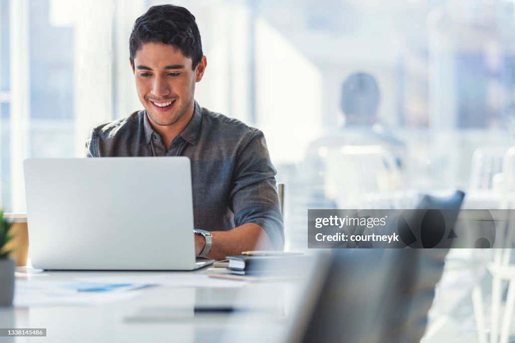 Geschäftsmann, der im Büro an einem Laptop arbeitet