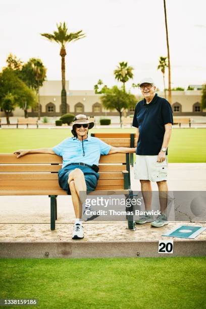Wide shot portrait of smiling senior men relaxing after lawn bowling match on summer evening