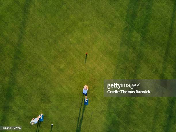 Aerial overhead extreme wide shot of senior man throwing bowl during lawn bowling match on summer evening