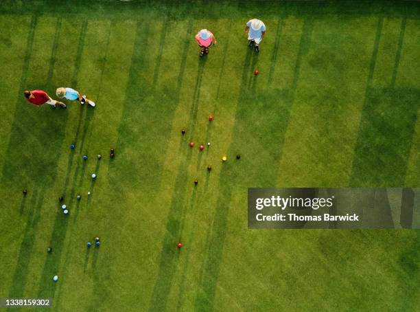 Aerial overhead extreme wide shot of senior lawn bowlers playing match on summer evening