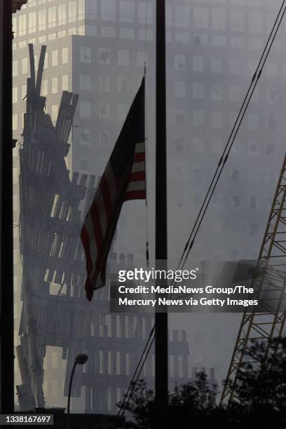Flags fly at half mast in front of the shell of what once was the Twin Towers of the World Trade Center, smoke still hanging in the air, on September...