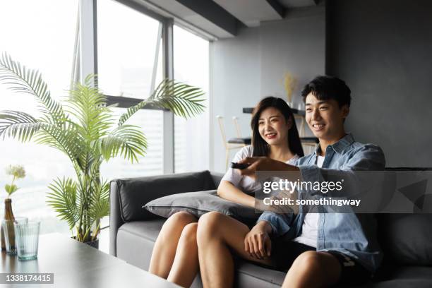 young couples watch tv at home - young couple watching tv stock pictures, royalty-free photos & images