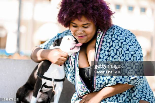 African American woman outdoors spends time together with cute pet dog Boston terrier outdoors