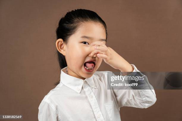 little girl pinching nose on brown background - girl hold nose stock pictures, royalty-free photos & images