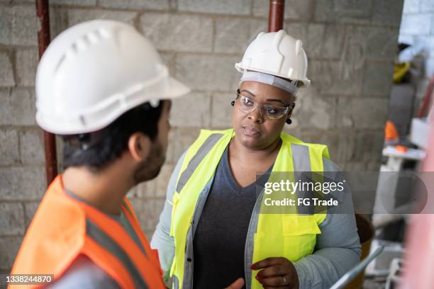 mitarbeiter, die ein meeting auf einer baustelle durchführen - foundations gender equality discussion stock-fotos und bilder