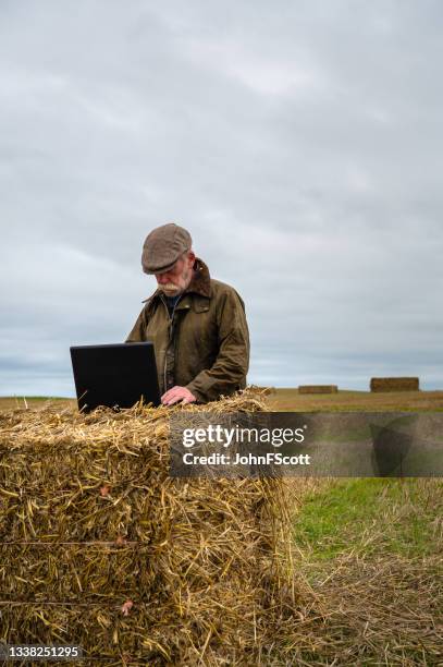 retired man using a laptop in a crop field - waxed jacket stock pictures, royalty-free photos & images