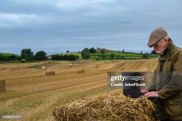 active senior man using a laptop in a crop field - waxed jacket stock pictures, royalty-free photos & images