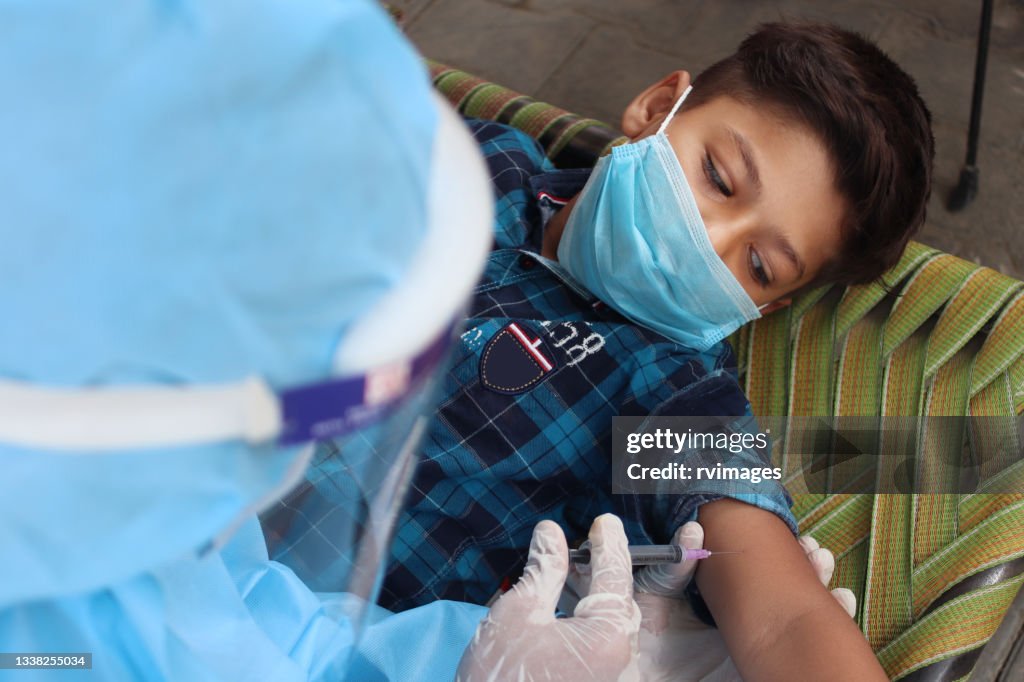 Doctor’s hands in surgical gloves preparing COVID-19 vaccine for child patient in India