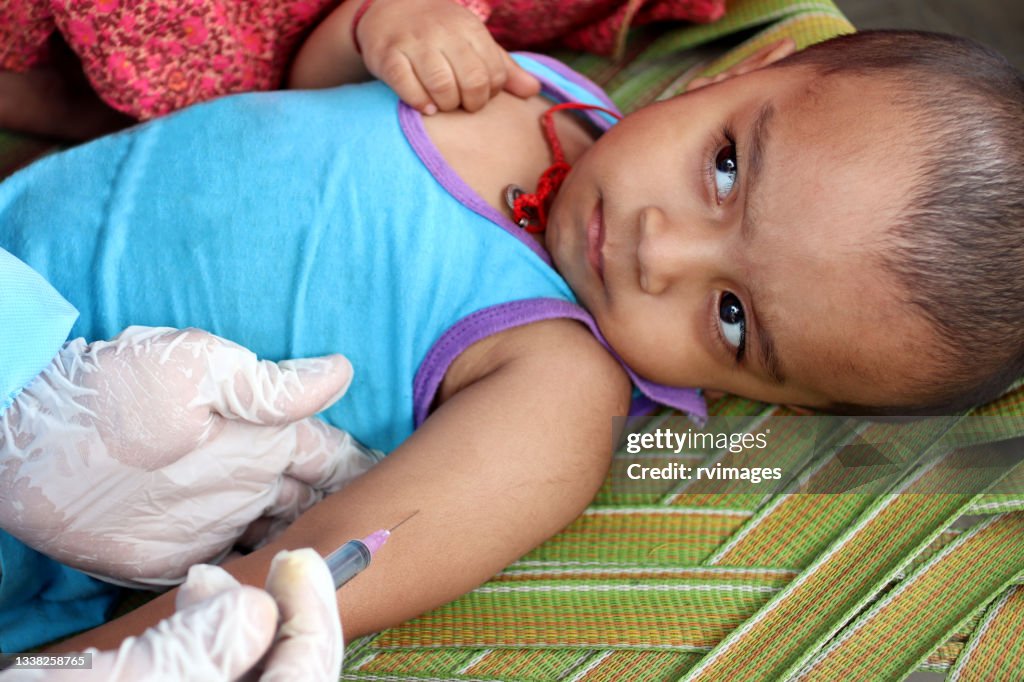 Doctor’s hands in surgical gloves preparing COVID-19 vaccine for baby patient in India