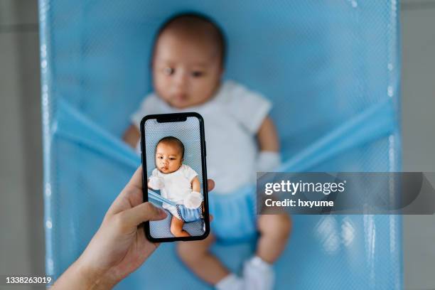 mujer tomando foto de su bebé con smartphone - photo messaging fotografías e imágenes de stock