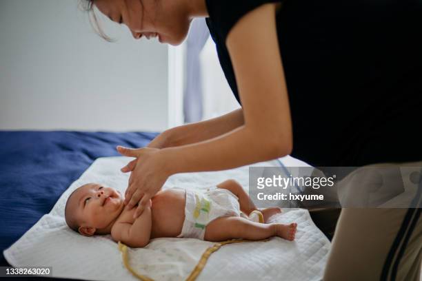 asiatische mutter tragen körperlotion für ihr baby nach dem baden auf - baby changing mat stock-fotos und bilder