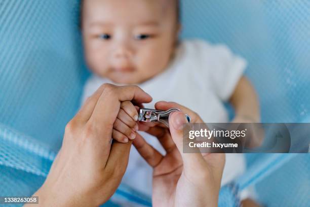 mother clipping nail of her baby at home - baby nail clippers stock pictures, royalty-free photos & images
