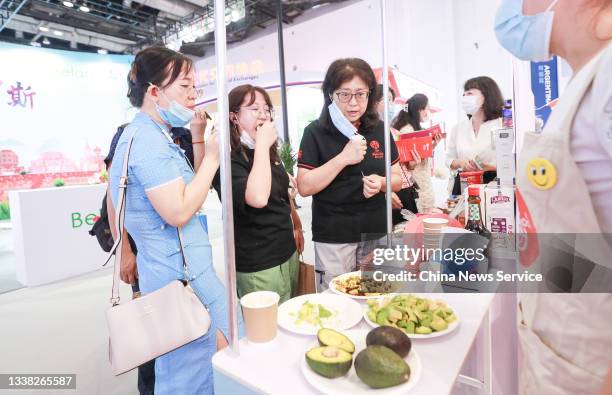 Visitors eat avocado at the booth of Peru during the 2021 China International Fair for Trade in Services at China National Convention Center on...