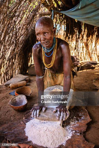 woman from karo tribe making sorghum flour, ethiopia, africa - karokultur bildbanksfoton och bilder