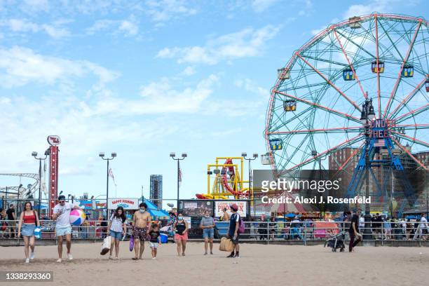 People walk on the beach at Coney Island over Labor Day Weekend on September 4, 2021 in the Brooklyn Borough of New York City. Some neighborhoods are...
