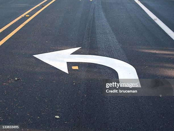 white turn left arrow painted on asphalt - alles stockfoto's en -beelden