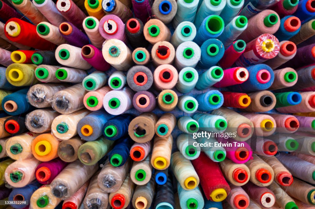 Large group of variation colourful sewing thread spool in small business work place studio