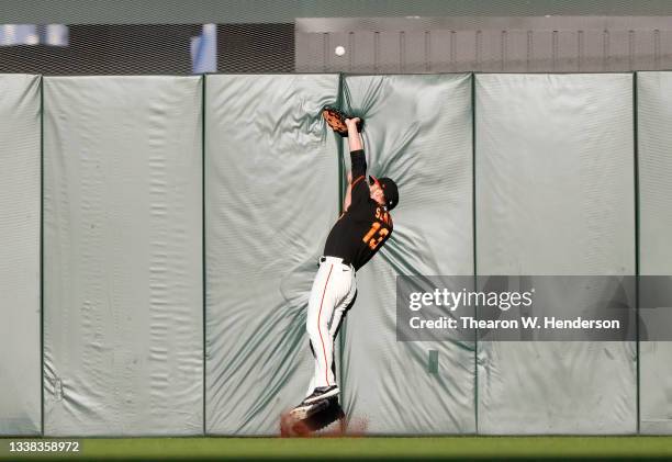 Austin Slater of the San Francisco Giants collides with the wall and watches the ball go over for a lead off solo home run by Trea Turner of the Los...