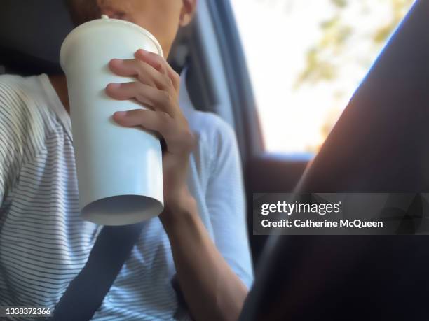 african-american woman enjoys a drink from a fast food restaurant while sitting in car behind the wheel - drinking soda in car stock pictures, royalty-free photos & images