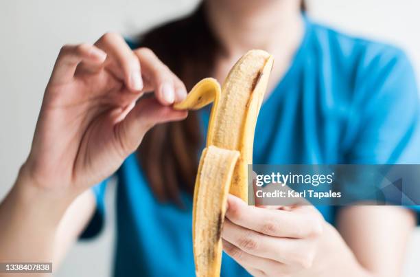 a young southeast asian woman is holding a ripe banana - casca de banana - fotografias e filmes do acervo