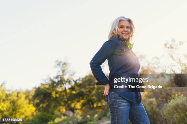 portrait of smiling mature woman against clear sky - woman jeans stock pictures, royalty-free photos & images