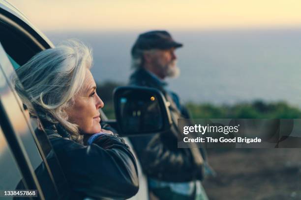 mature woman sitting in car during sunset - happy retirement stock pictures, royalty-free photos & images