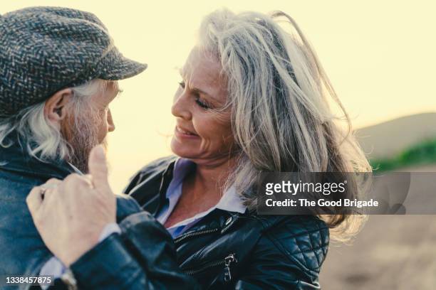 smiling woman embracing husband at sunset - aged to perfection stock pictures, royalty-free photos & images