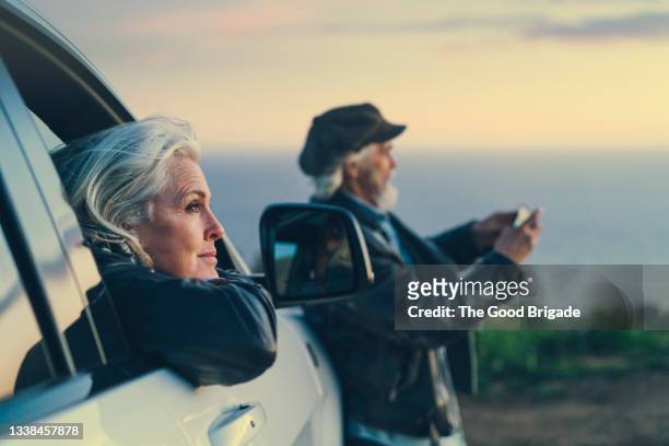 Senior couple enjoying view of sunset from car
