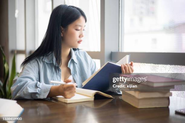 young student doing assignments and looking a book - woman reading script stock pictures, royalty-free photos & images