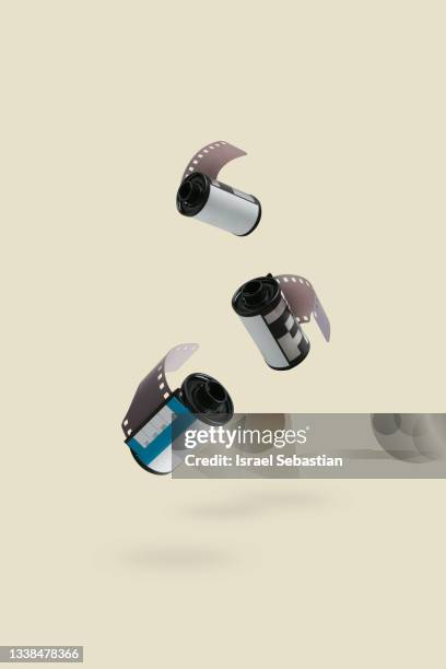 vertical image of a small group of analog film reels floating on yellow background. film is not dead - gravity film stock pictures, royalty-free photos & images