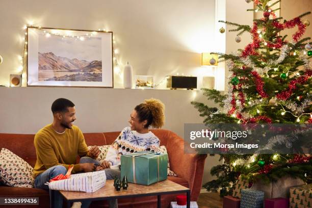 cheerful couple enjoying christmas at home - celebrate living stockfoto's en -beelden